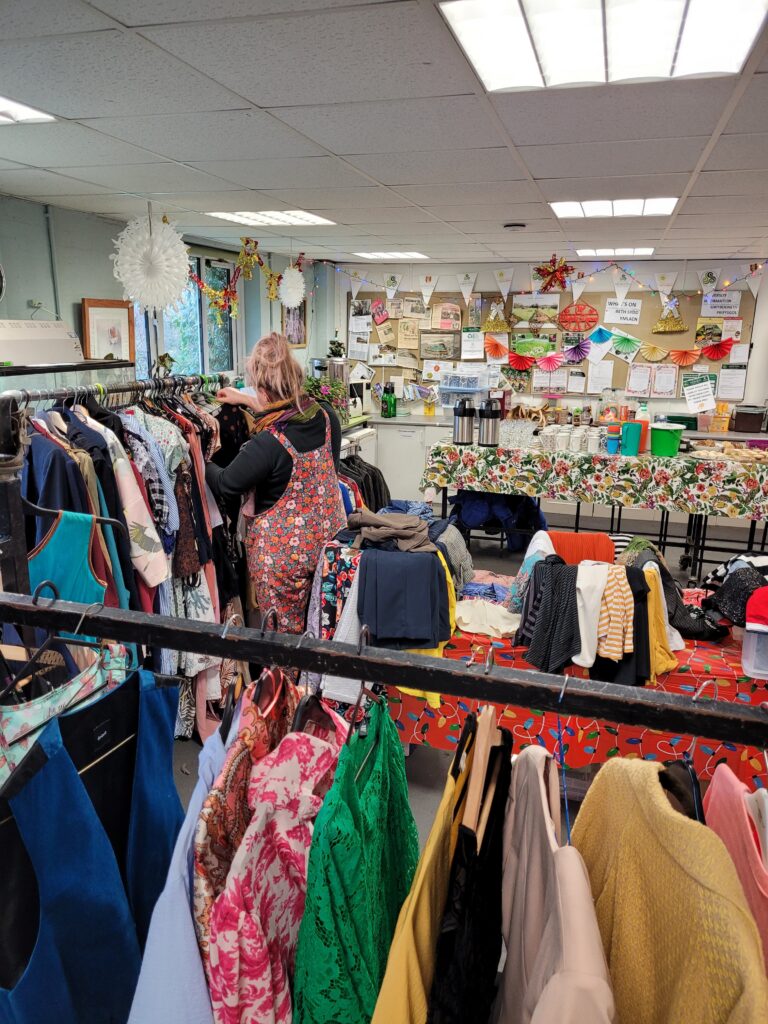 Rails of clothes in a community room decorated for Christmas